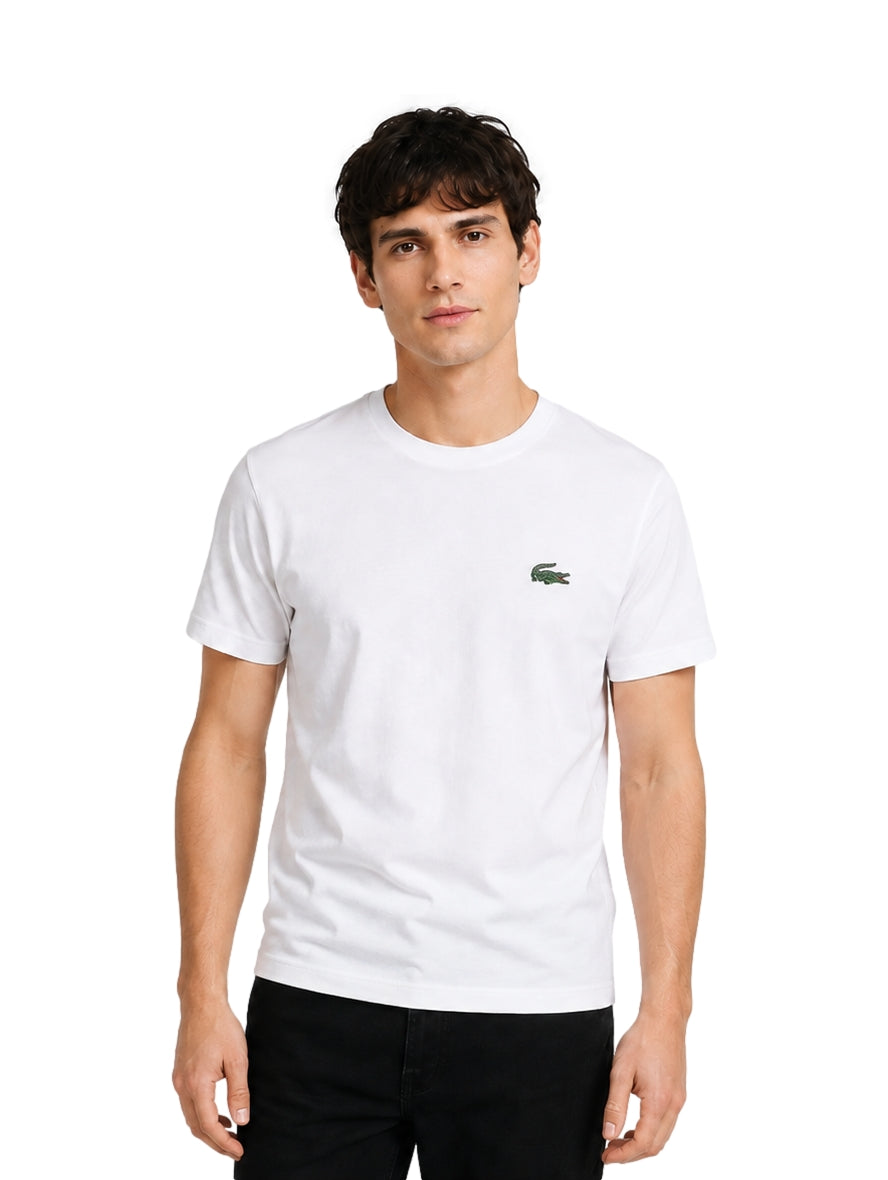Hombre vistiendo una playera blanca de manga corta marca Lacoste con logo pequeño en el pecho.