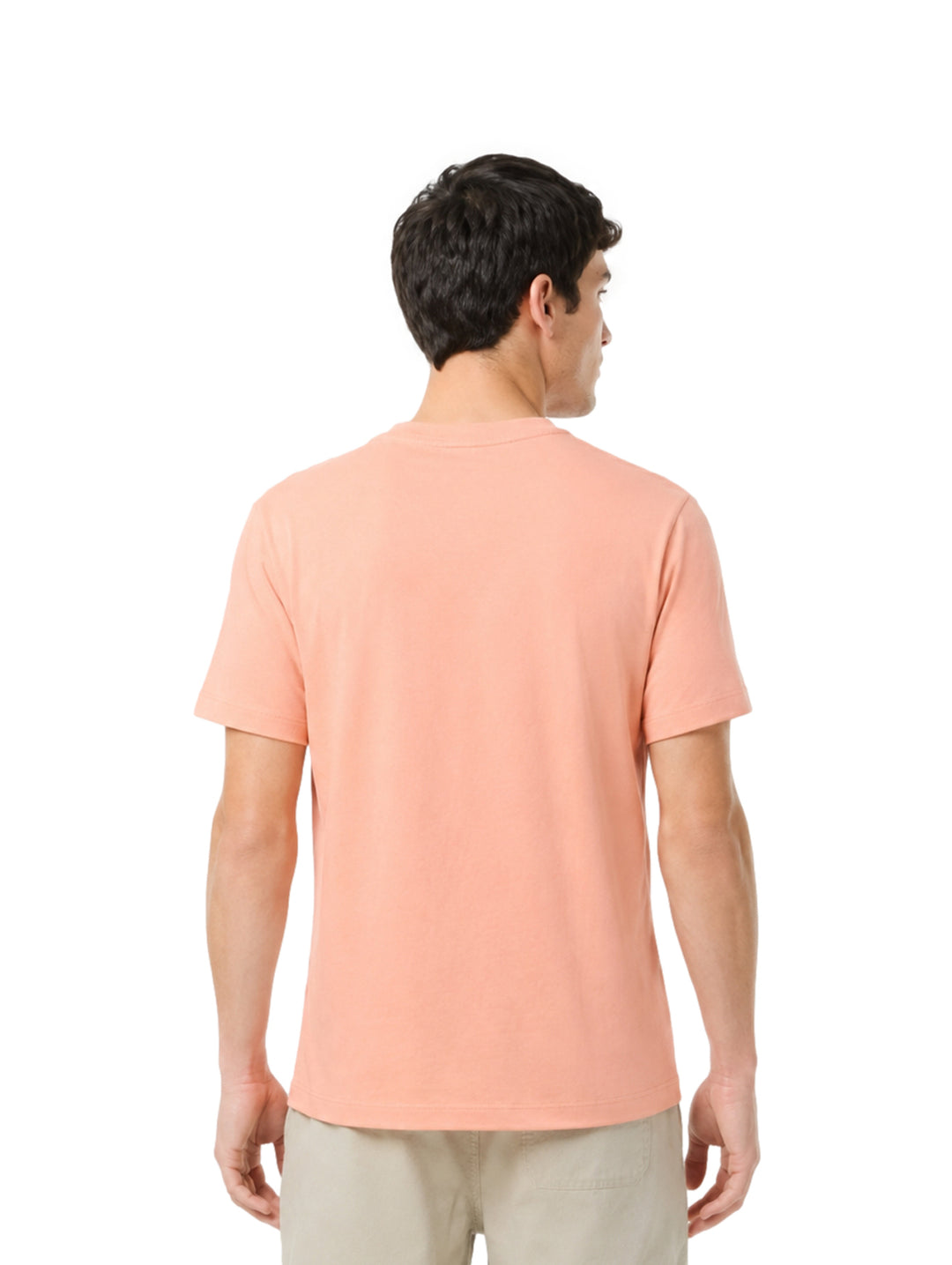 Hombre vistiendo una playera Lacoste de color salmón con cuello redondo y manga corta.
