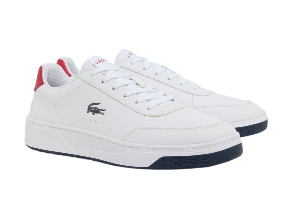 Tenis blancos Lacoste con suela azul marino y detalle rojo en el talón.
