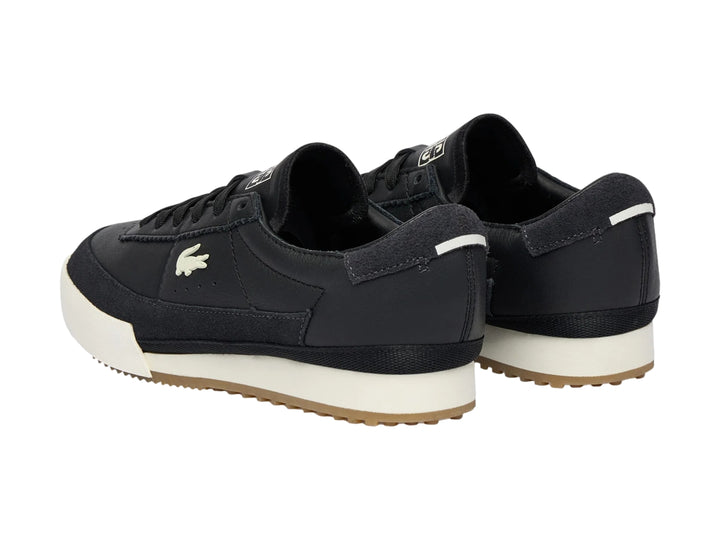 Tenis Lacoste de cuero negro con suela blanca y base de goma marrón.