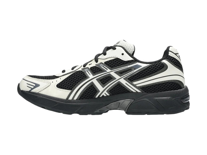Tenis deportivos ASICS GEL-1130 en colores negro y crema con detalles en malla y suela negra.