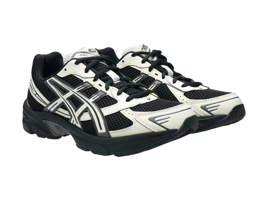 Tenis deportivos ASICS GEL-1130 en color negro y crema con suela negra y detalles en malla.