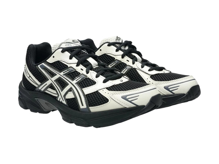 Tenis deportivos ASICS GEL-1130 en color negro y crema con suela negra y detalles en malla.