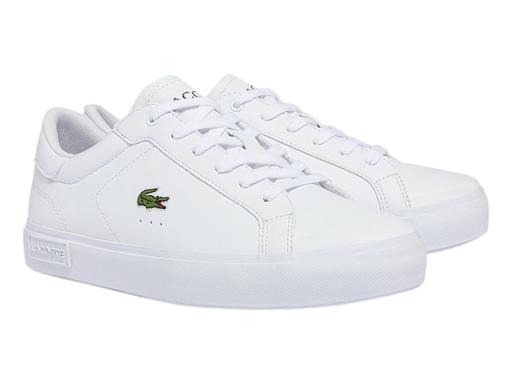 Tenis deportivos Lacoste color blanco para niño con logotipo del cocodrilo en el lateral y suela blanca.