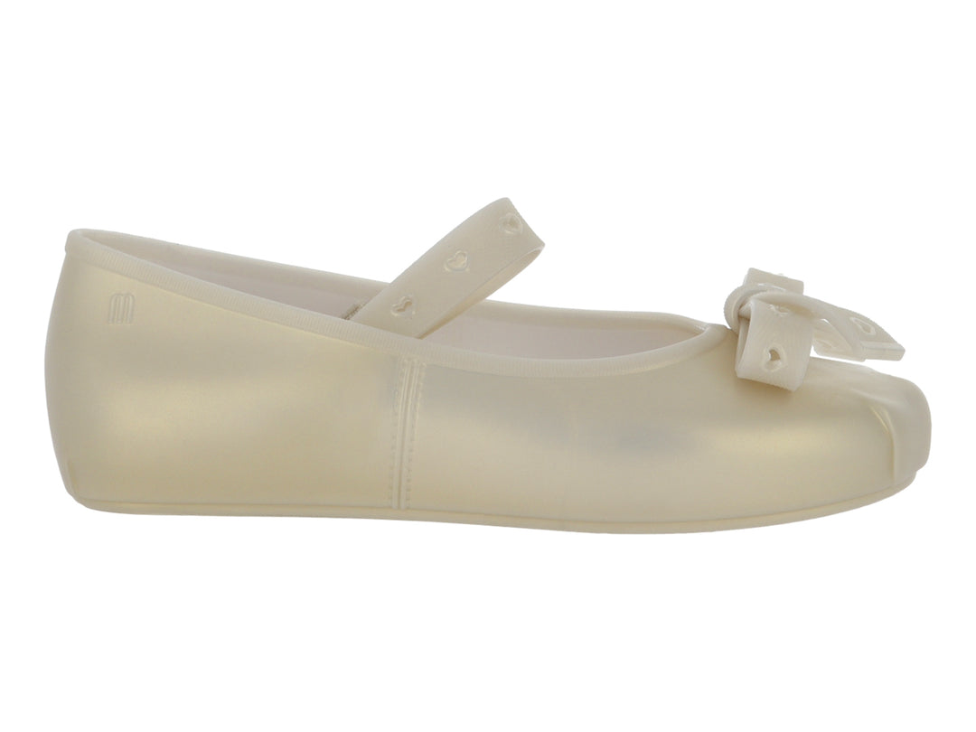 Zapato plano color beige para niña con moño frontal y correa con detalles de corazones.