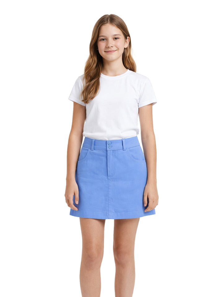 Niña modelando una falda corta color azul cielo y camiseta blanca sobre fondo blanco.