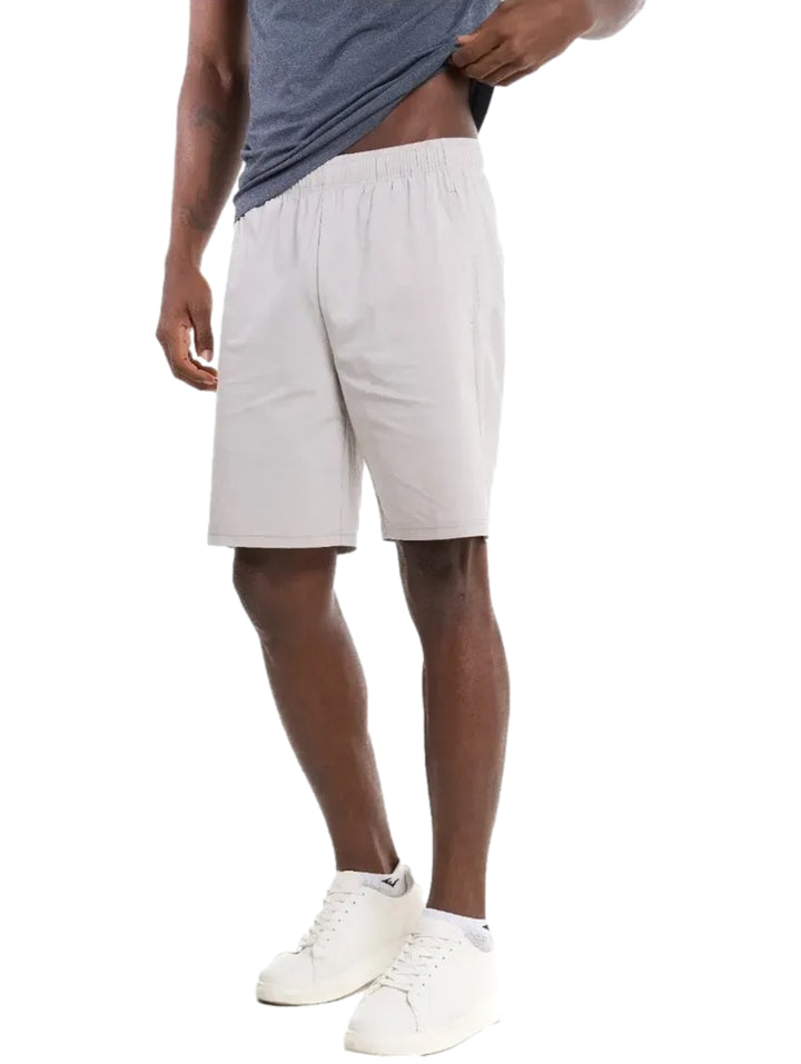 Hombre vistiendo shorts deportivos de color gris claro con tenis blancos.