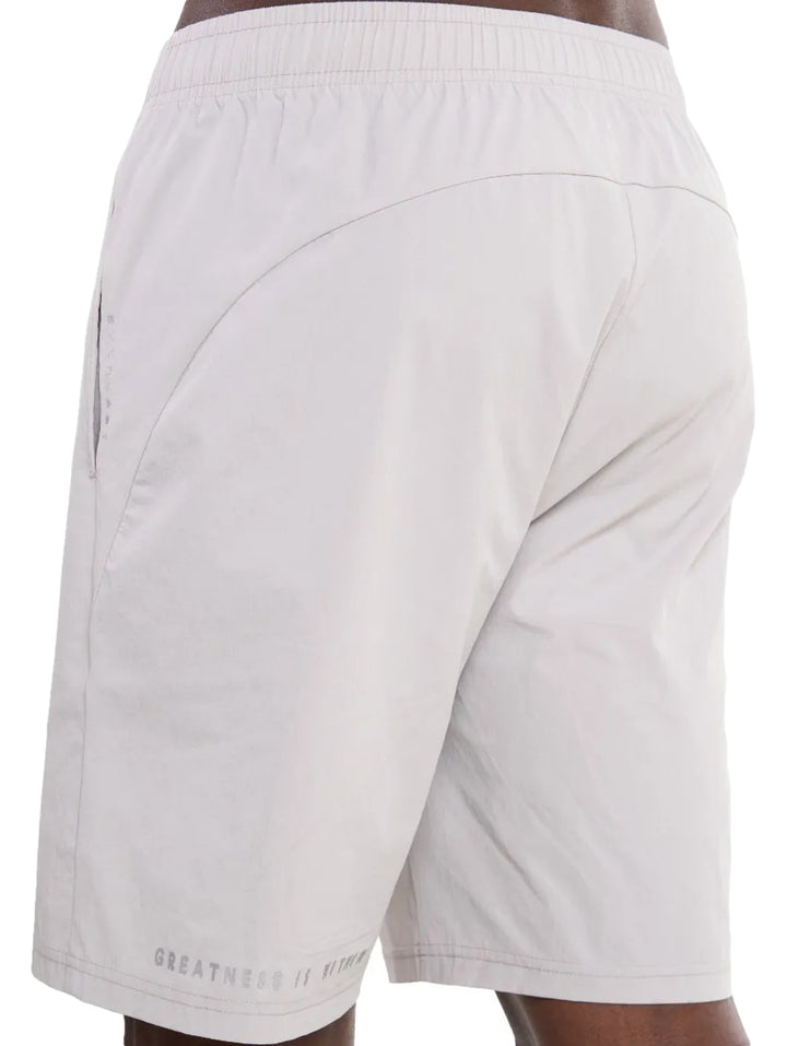 Hombre vistiendo shorts deportivos de color gris claro con tenis blancos.