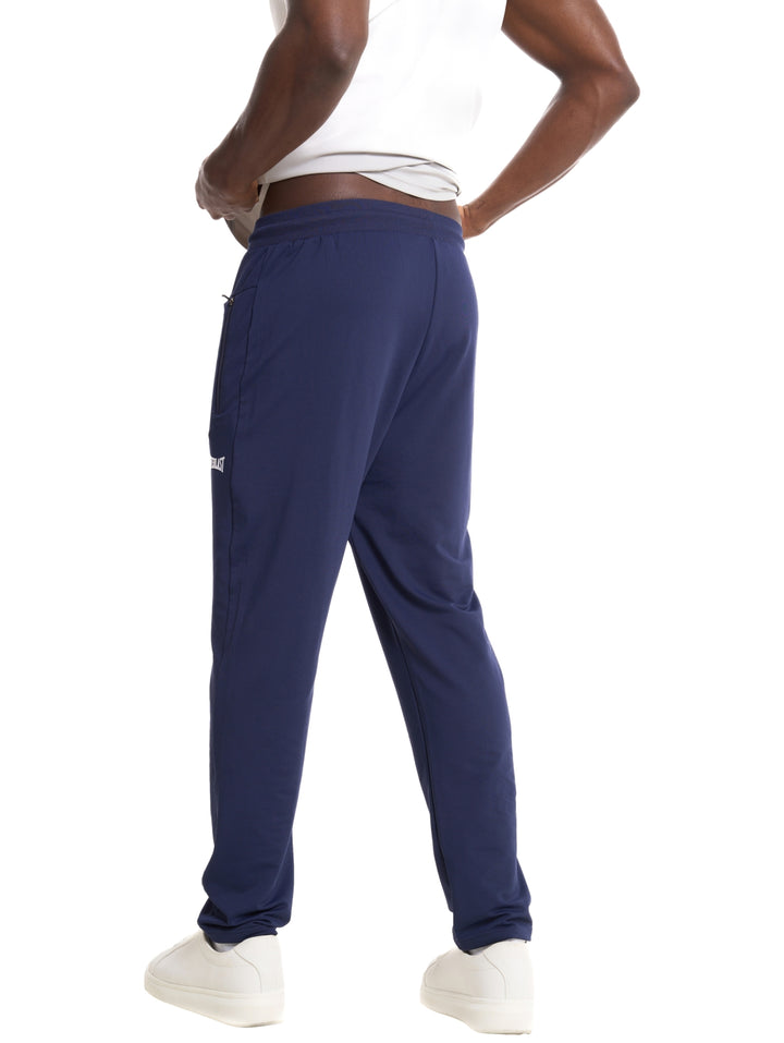 Hombre vistiendo pantalón deportivo Everlast color azul marino con logotipo blanco.
