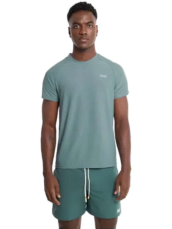 Hombre modelando playera deportiva de color verde con cuello redondo y manga corta.