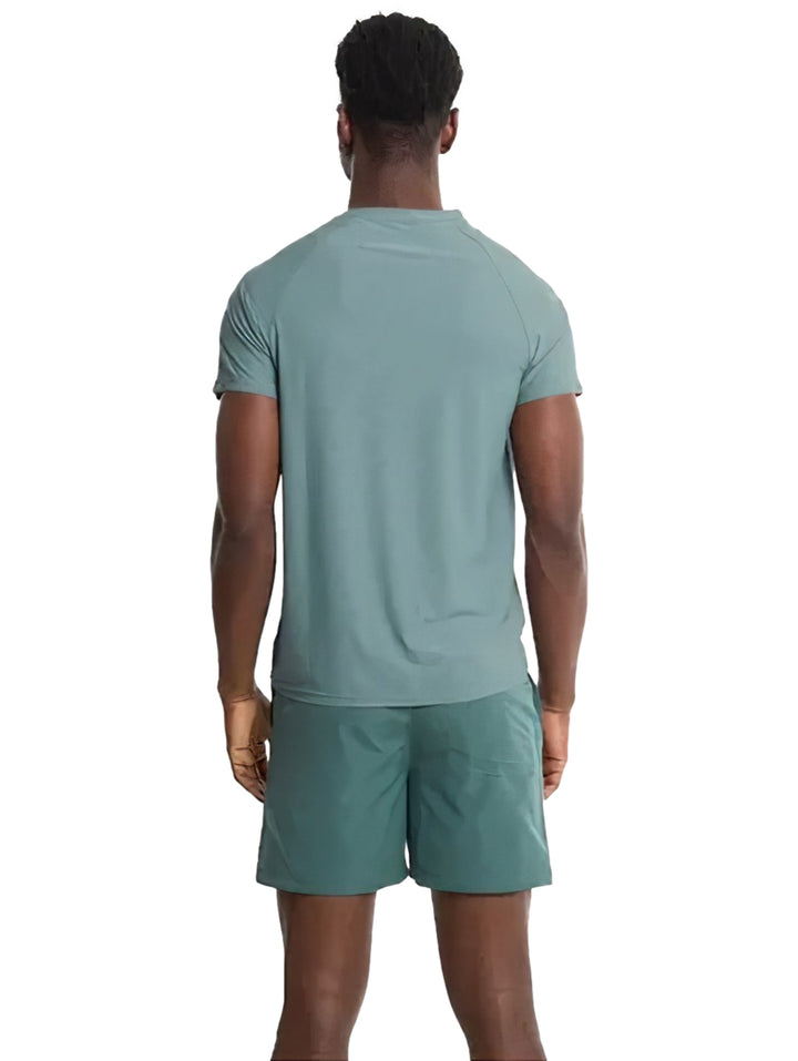 Hombre modelando playera deportiva de color verde con cuello redondo y manga corta.