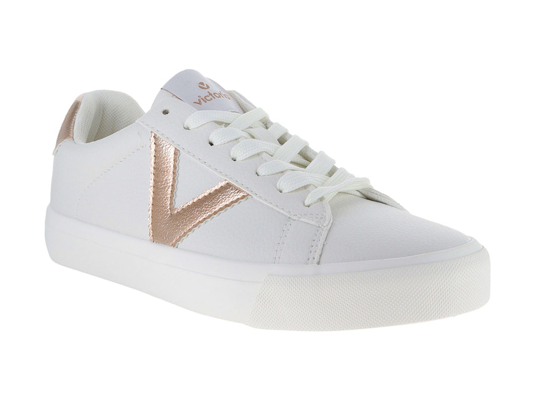 Tenis blancos Victoria con detalles metálicos en oro rosa y cordones blancos.