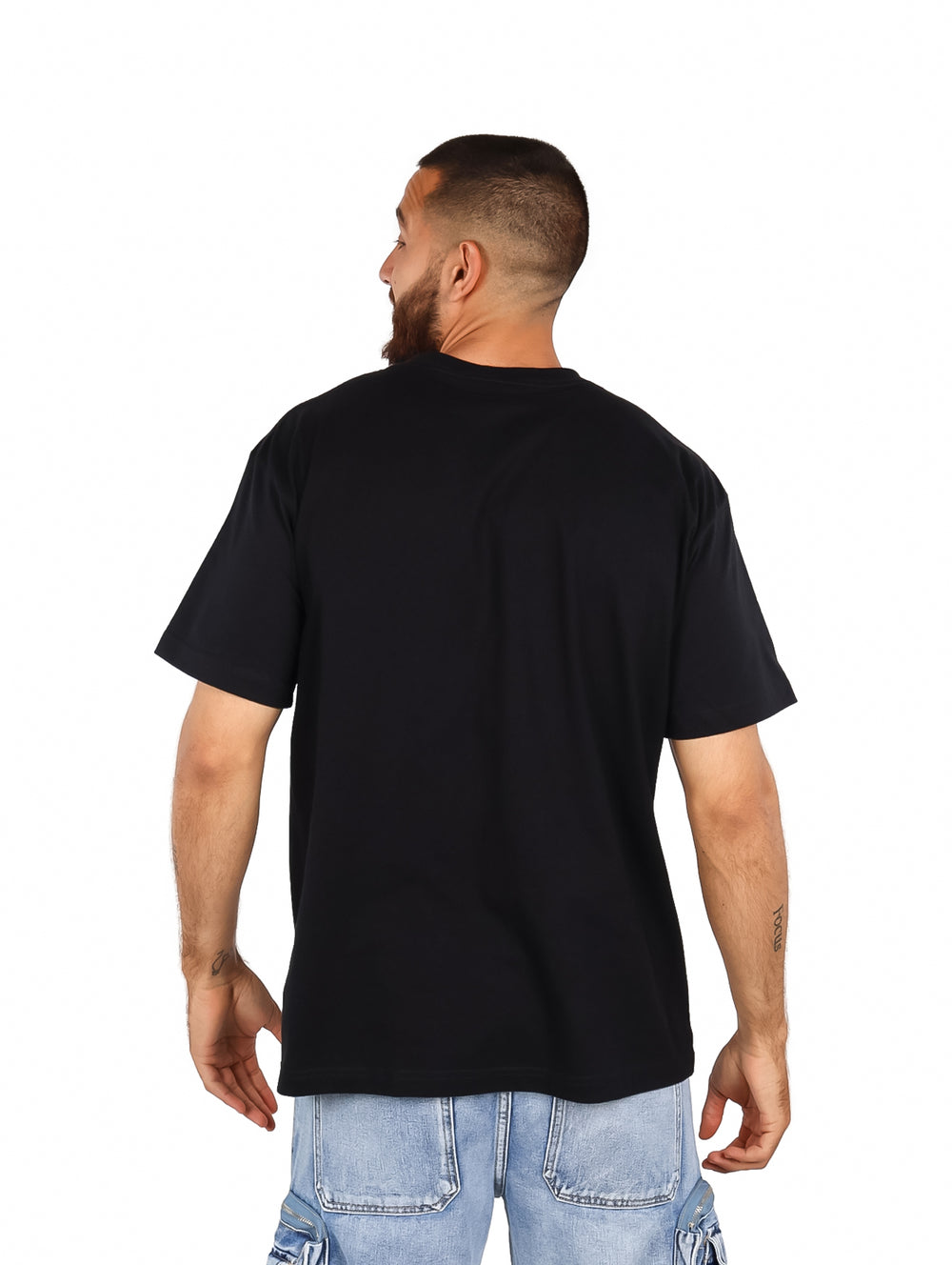 Hombre vistiendo playera negra oversized con estampado frontal de personajes de Dragon Ball en colores rojo y blanco.