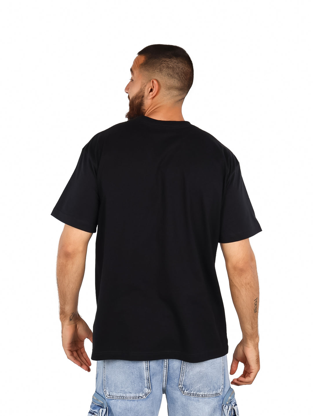 Hombre vistiendo playera negra oversized con estampado frontal de personajes de Dragon Ball en colores rojo y blanco.