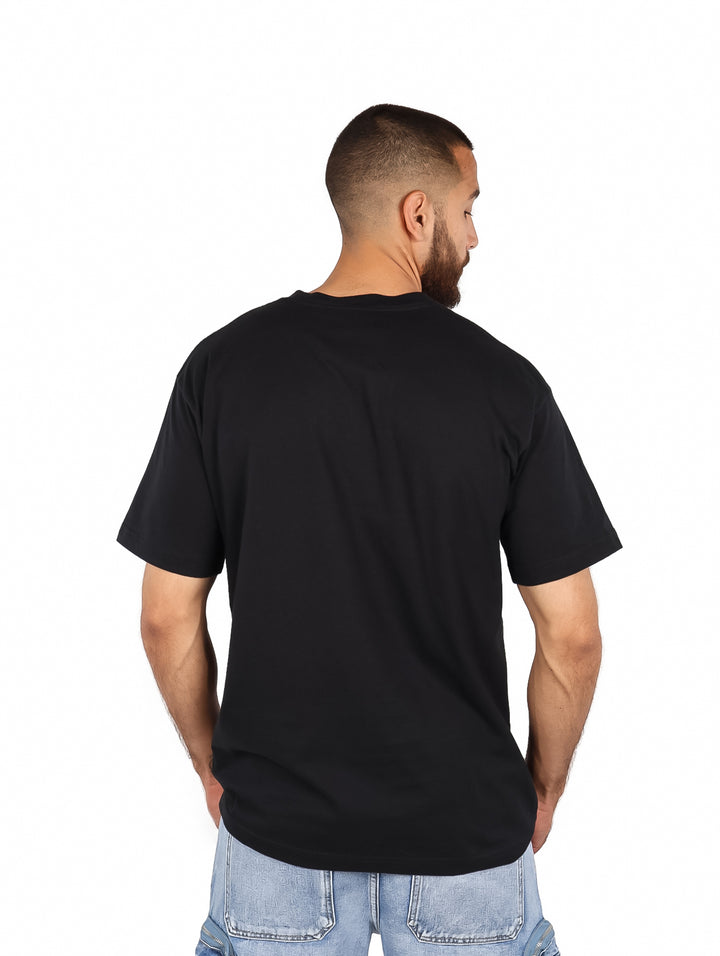 Hombre vistiendo playera negra oversized con estampado naranja de Pochita de Chainsaw Man.