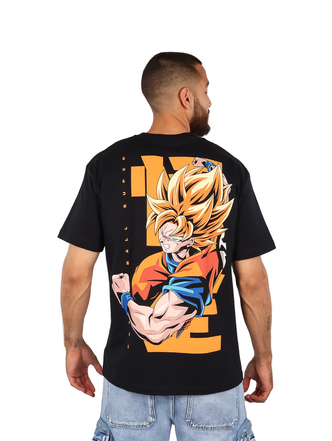 Hombre vistiendo playera negra oversized con estampado circular de Dragon Ball en el pecho.