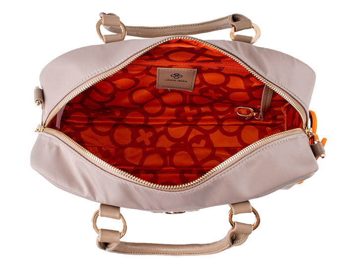 Bolsa de mano color taupe con asa superior, detalles dorados y un accesorio colgante color naranja.