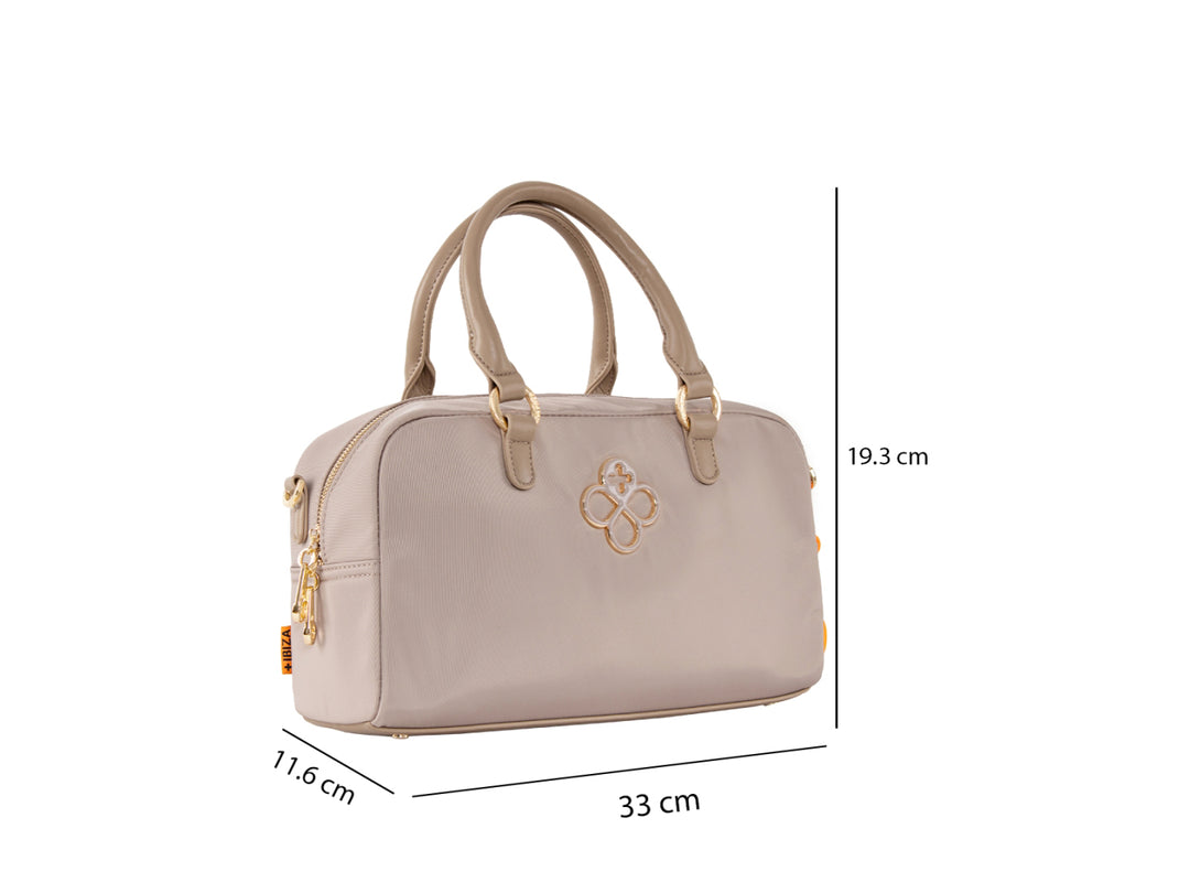 Bolsa de mano color taupe con asa superior, detalles dorados y un accesorio colgante color naranja.