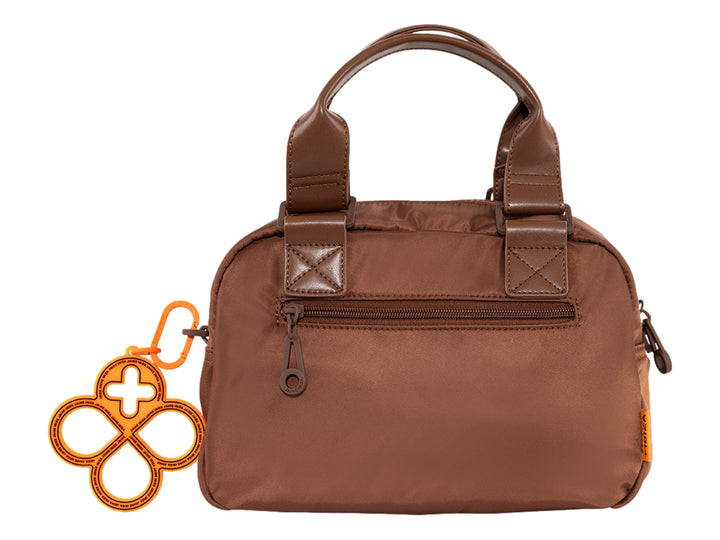 Bolsa de mano color cocoa con asa superior y un accesorio colgante circular color naranja.