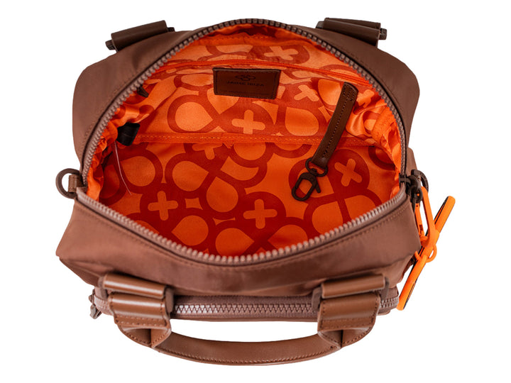 Bolsa de mano color cocoa con asa superior y un accesorio colgante circular color naranja.