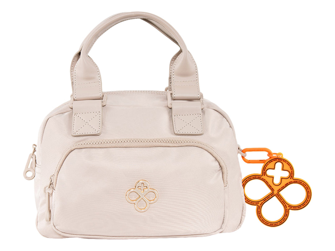 Bolsa de mano color beige de Jaime Ibiza con asa superior y un accesorio decorativo naranja.