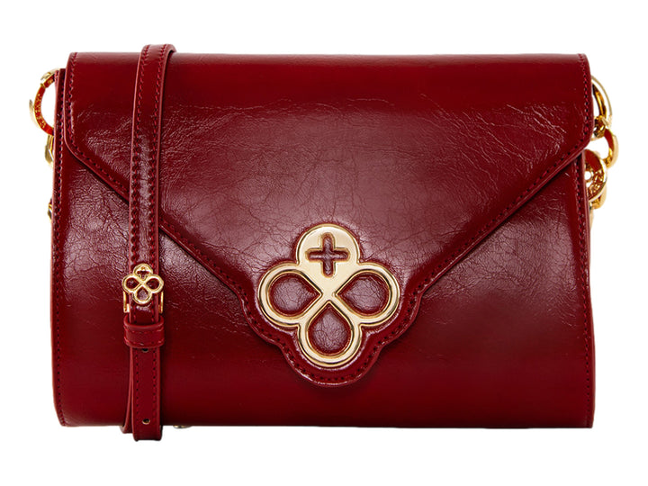 Bolsa roja de cuero con herraje dorado central y correa ajustable.