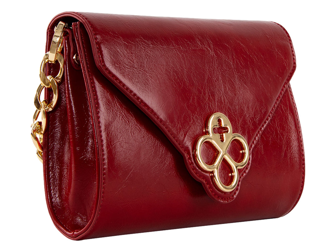 Bolsa roja de cuero con herraje dorado central y correa ajustable.