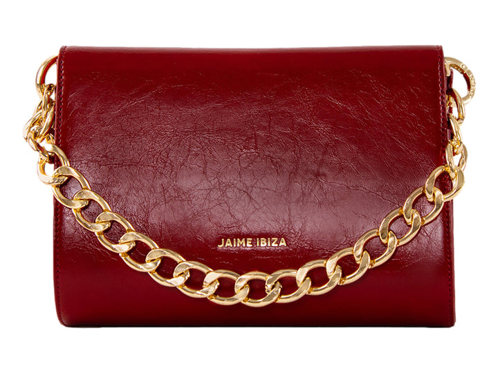 Bolsa roja de cuero con herraje dorado central y correa ajustable.