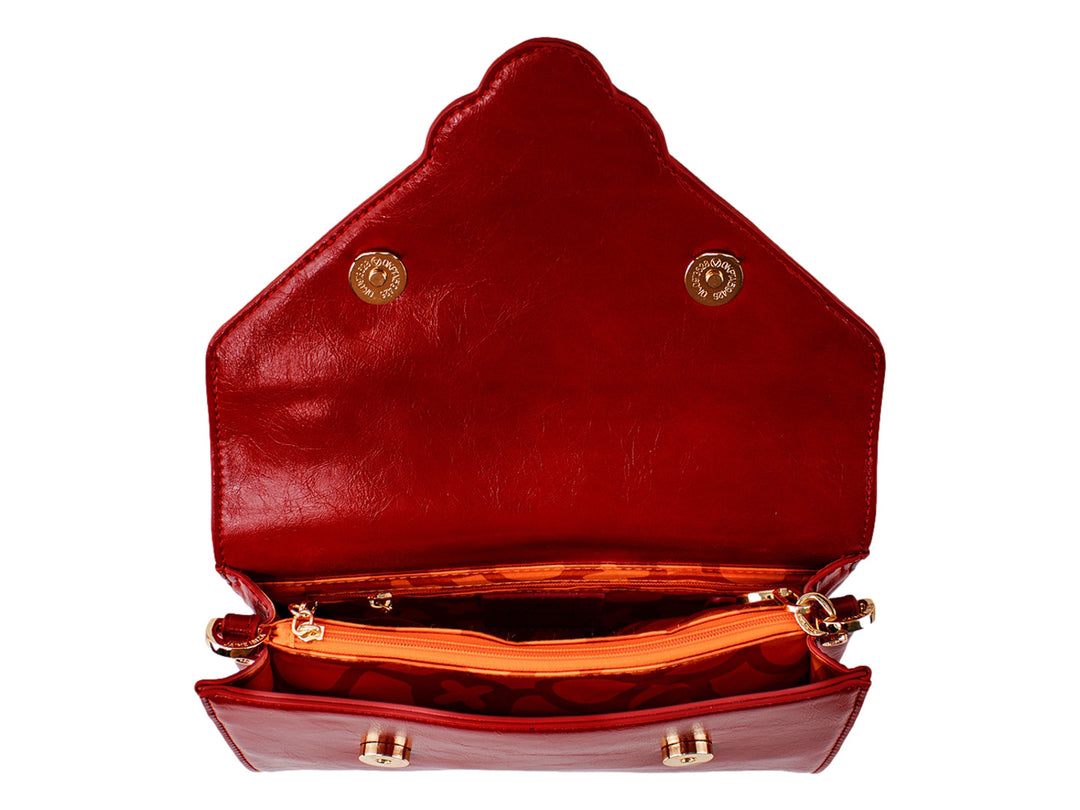 Bolsa roja de cuero con herraje dorado central y correa ajustable.