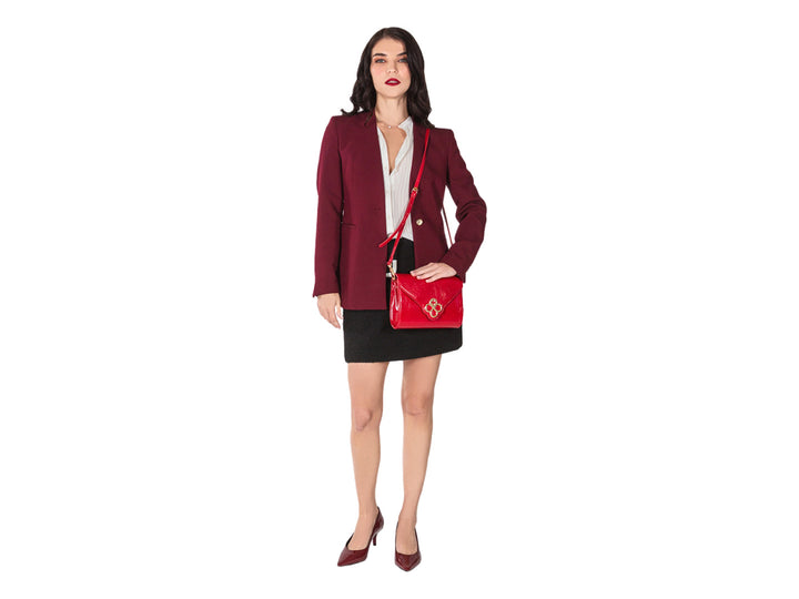 Bolsa roja de cuero con herraje dorado central y correa ajustable.