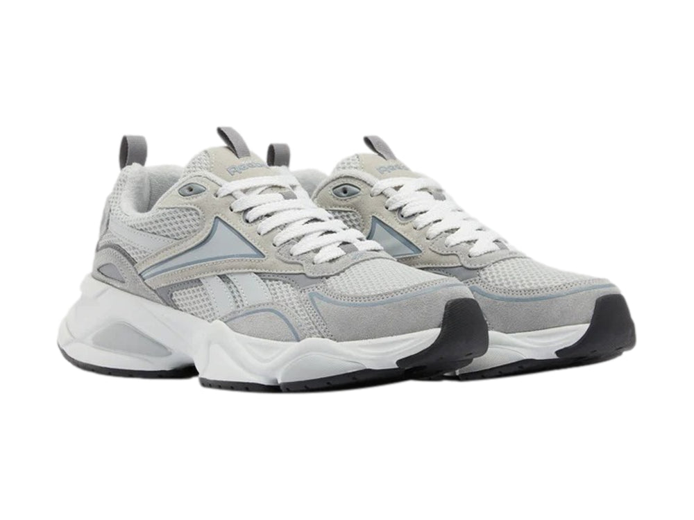 Tenis deportivos Reebok color gris y blanco con suela gruesa y detalles de malla.
