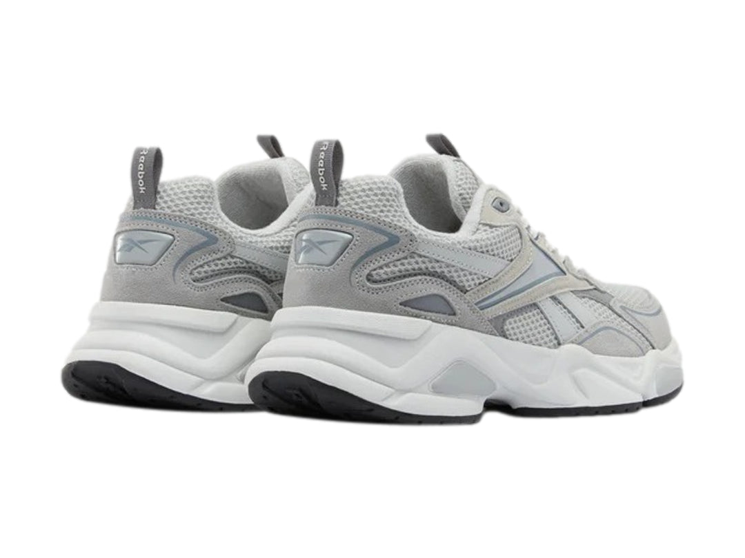 Tenis deportivos Reebok color gris y blanco con suela gruesa y detalles de malla.