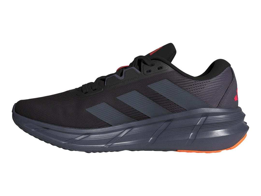 Tenis deportivos Adidas Questar 3 en color negro con detalles en rojo y naranja en la suela.
