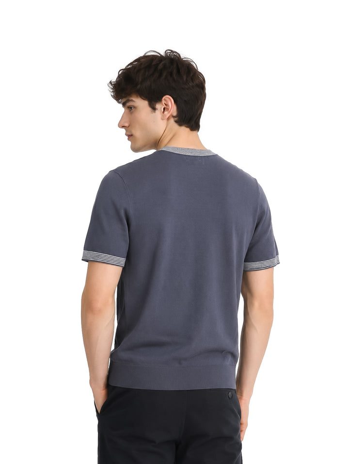 Hombre vistiendo playera tejida color gris con detalles blancos en cuello y mangas.