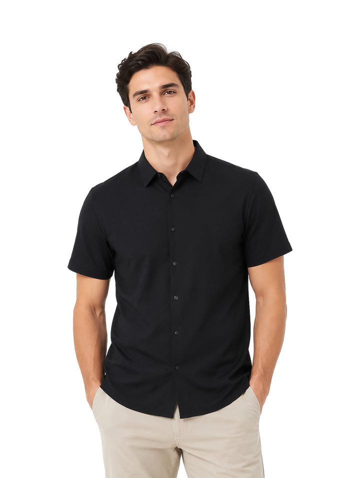 Hombre vistiendo una camisa negra de manga corta y pantalones beige sobre fondo blanco.