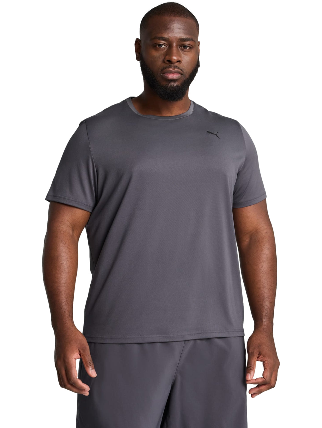 Hombre vistiendo una camiseta deportiva de color gris oscuro de la marca PUMA con cuello redondo y manga corta.