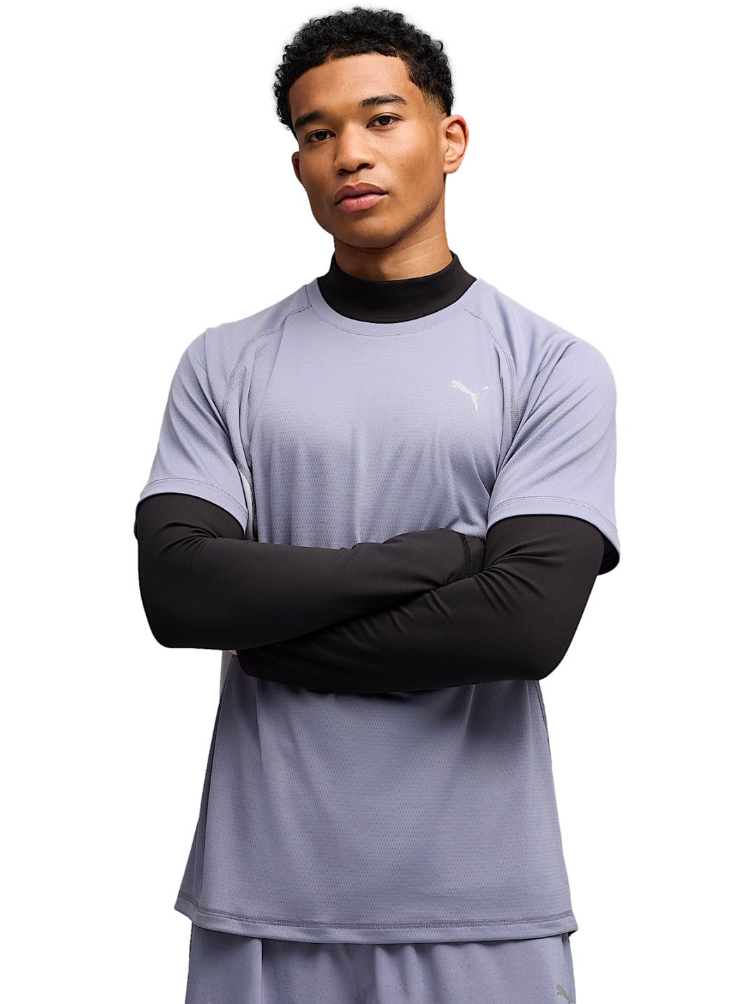Hombre vistiendo camiseta deportiva PUMA color plata vibrante sobre una prenda negra de manga larga.