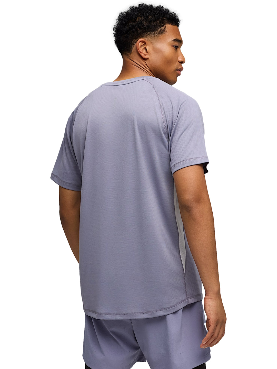 Hombre vistiendo camiseta deportiva PUMA color plata vibrante sobre una prenda negra de manga larga.