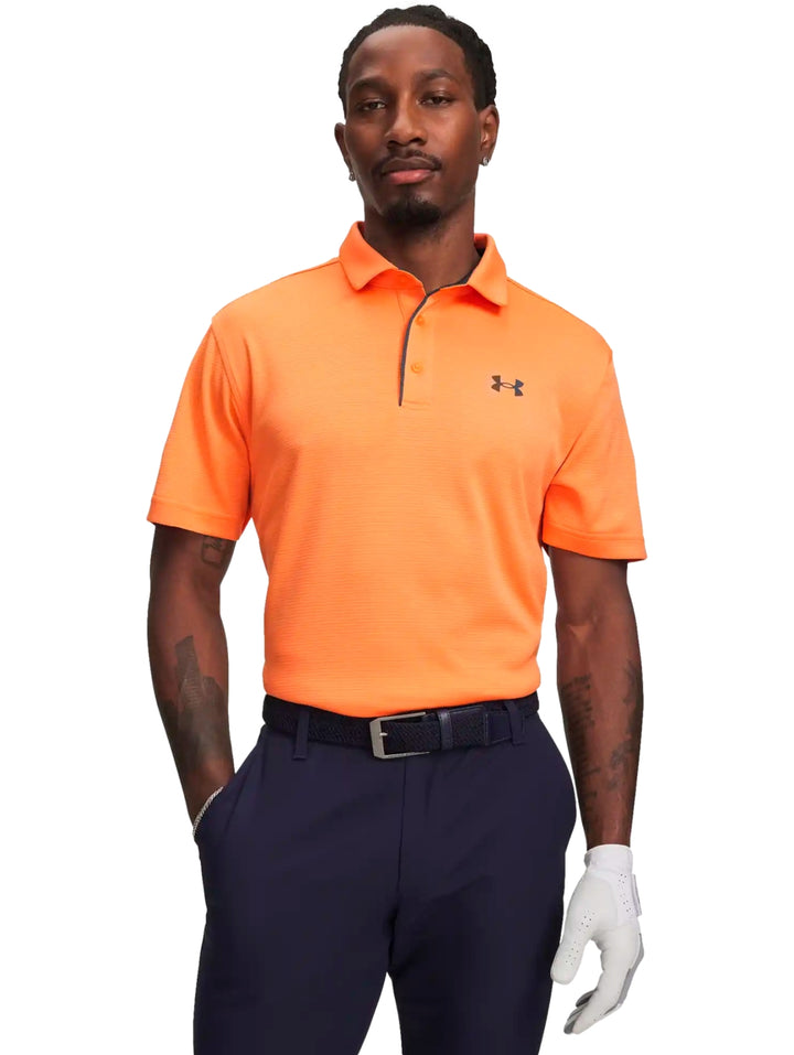 Hombre vistiendo una playera polo deportiva de color naranja de la marca Under Armour.