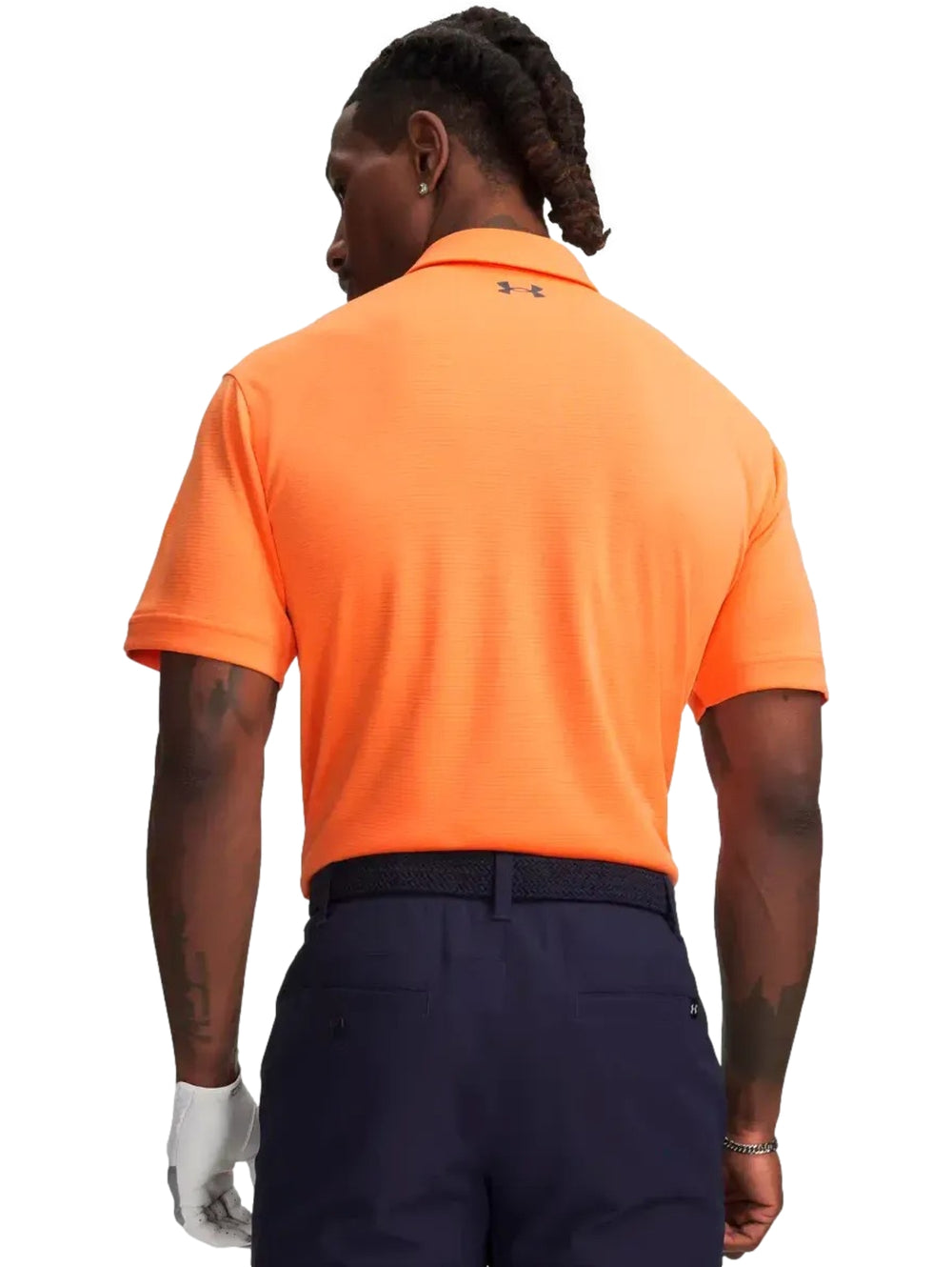 Hombre vistiendo una playera polo deportiva de color naranja de la marca Under Armour.