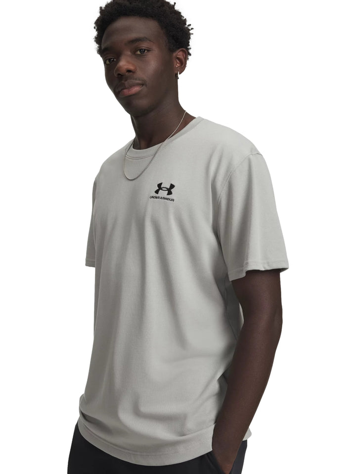 Hombre vistiendo una playera de manga corta color gris con logotipo de Under Armour en el pecho.