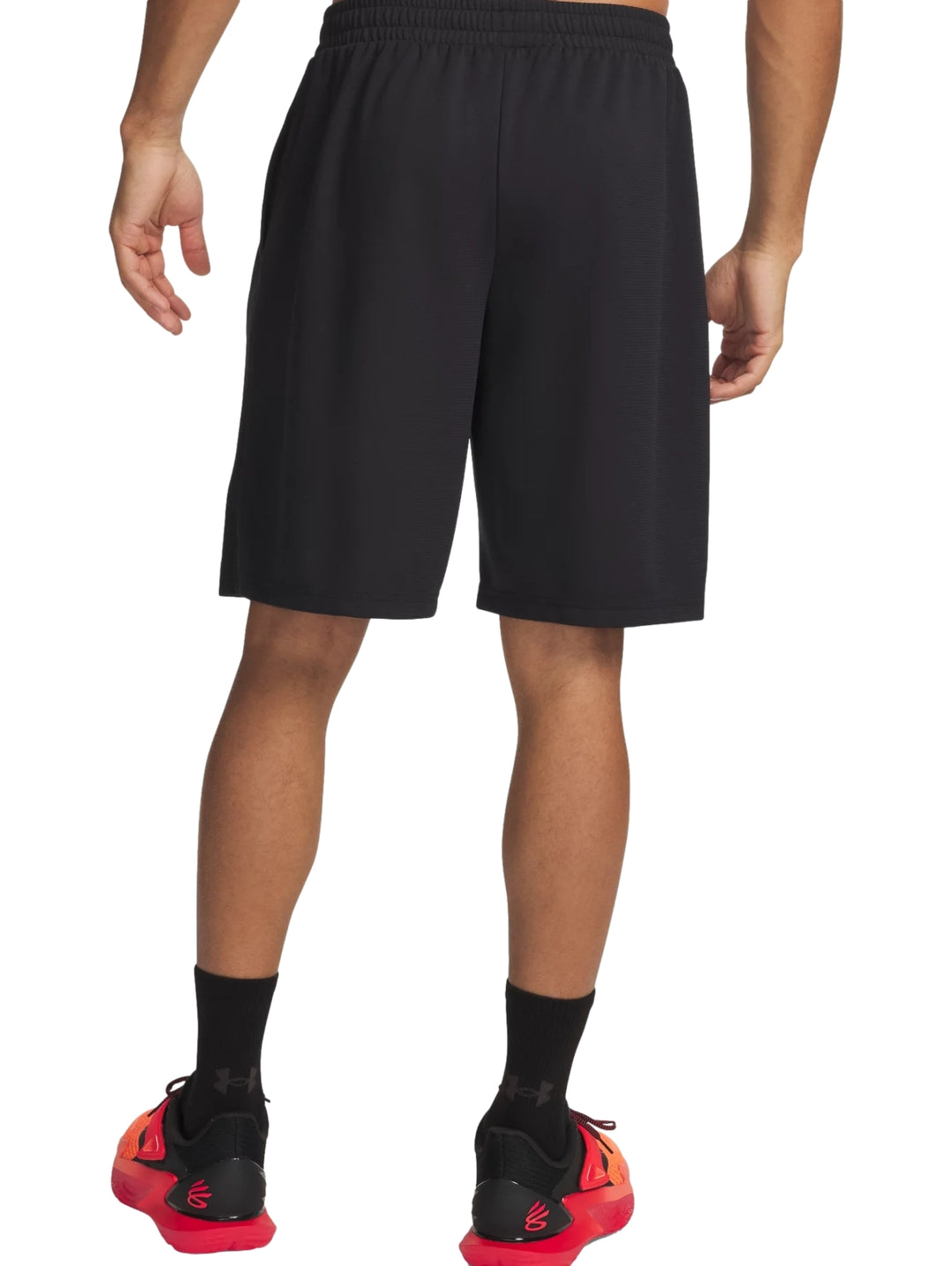 Hombre vistiendo shorts deportivos color negro de la marca Under Armour con logos blancos laterales.
