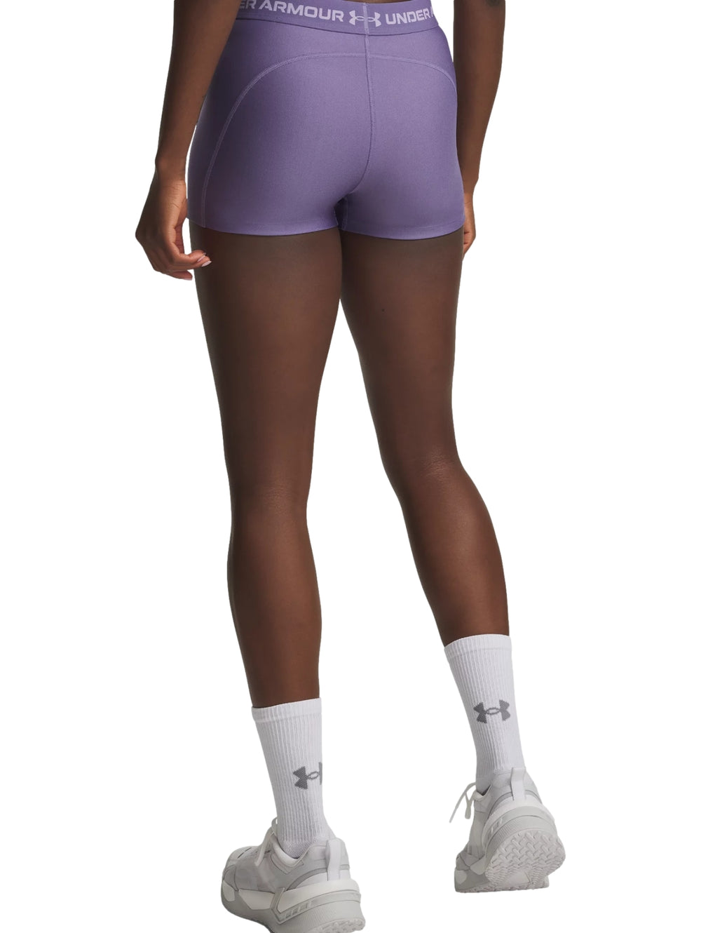 Mujer vistiendo shorts deportivos ajustados de color morado de la marca Under Armour.