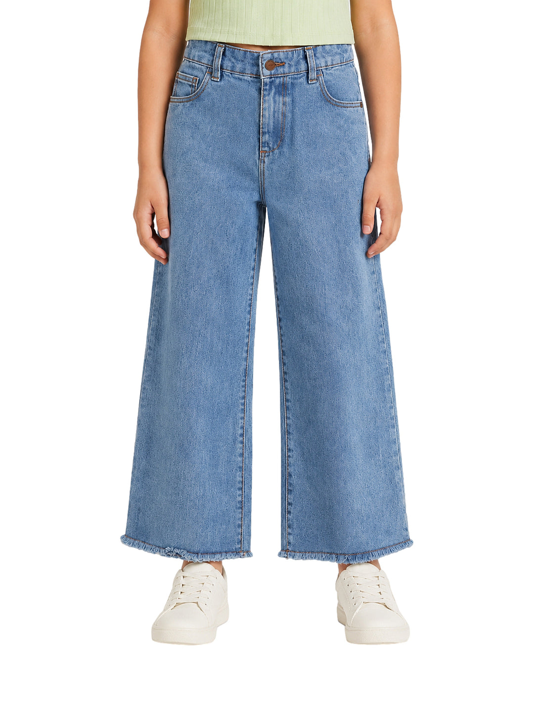 Jeans azules de pierna ancha para niña con bajos deshilachados.
