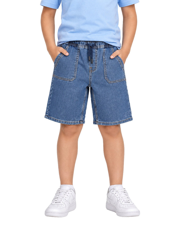 Niño vistiendo un short de mezclilla azul con cintura elástica y cordón ajustable.