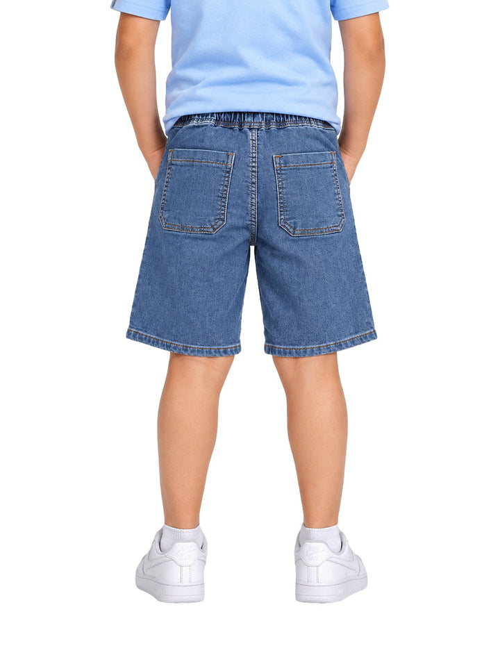 Niño vistiendo un short de mezclilla azul con cintura elástica y cordón ajustable.