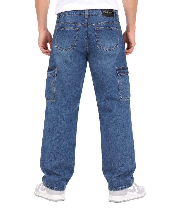 Hombre vistiendo jeans baggy color azul stone con bolsillos cargo laterales y tenis blancos.