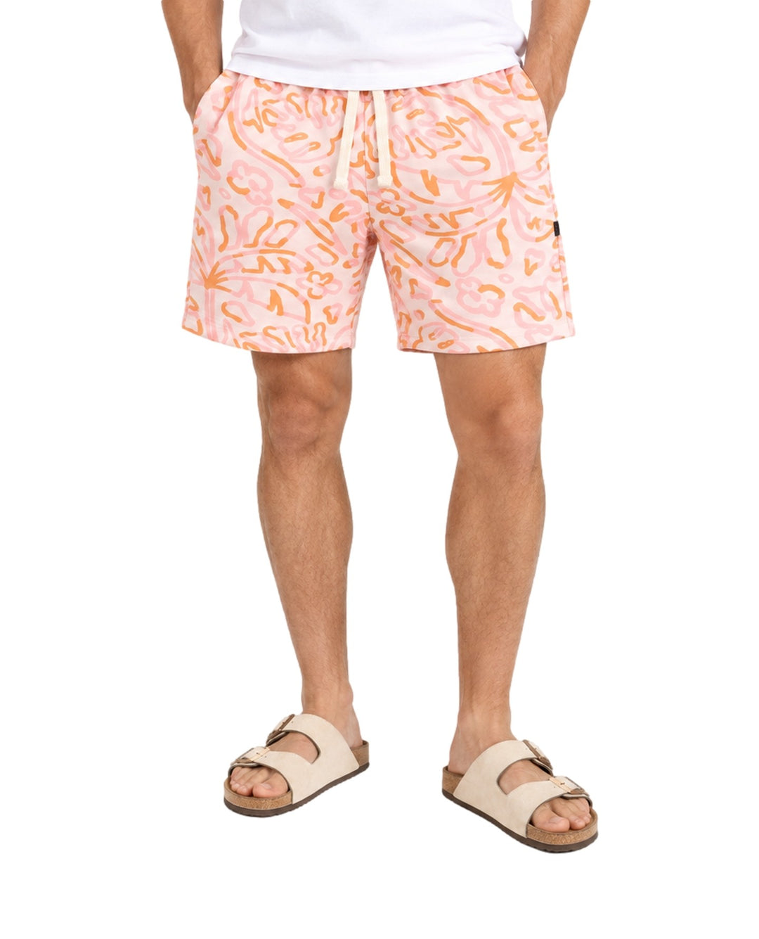 Hombre vistiendo short de baño Action Gear color hueso con estampado abstracto en tonos rosa y naranja.