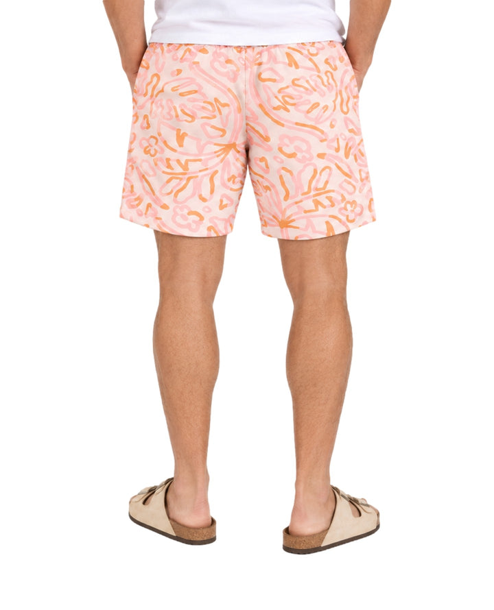 Hombre vistiendo short de baño Action Gear color hueso con estampado abstracto en tonos rosa y naranja.