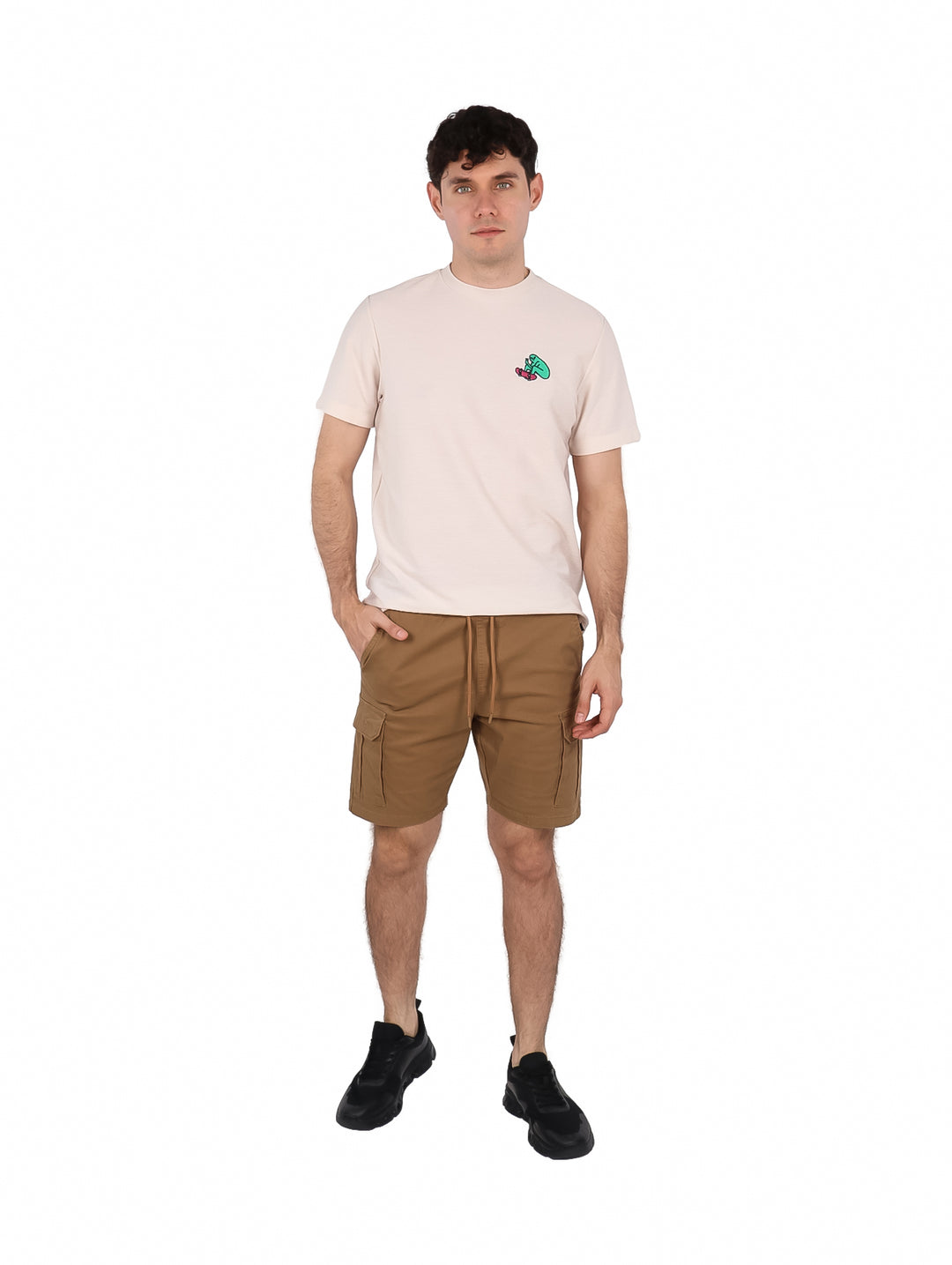 Hombre vistiendo playera de manga corta color hueso con un pequeño estampado en el pecho.
